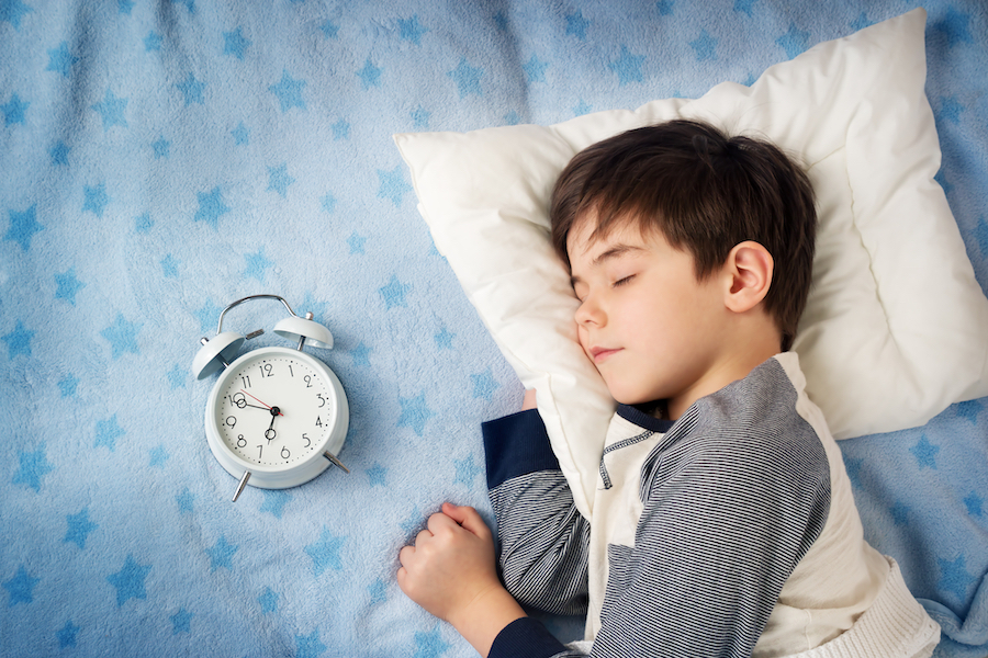 Six Years Old Child Sleeping In Bed With Alarm Clock